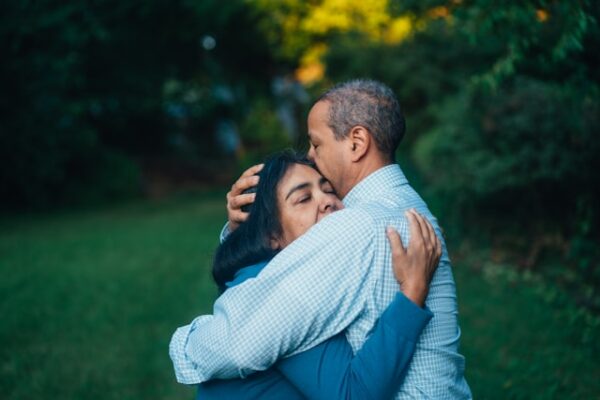 A couple embracing warmly in a peaceful outdoor setting, symbolizing reconciliation and the healing power of forgiveness.