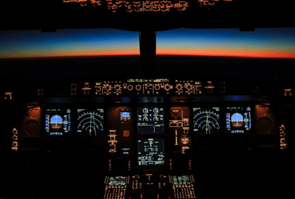 A cockpit illuminated by various controls and screens, illustrating how to begin Understanding the Four Stages of Competence in the Christian Journey
